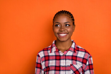 Photo of sweet cute woman dressed plaid shirt looking empty space smiling isolated shine vibrant orange color background