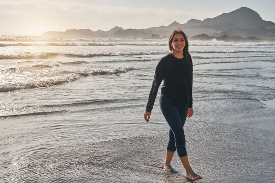 portrait of young latin woman walking along the shore of the beach happy at sunset in Atacama region