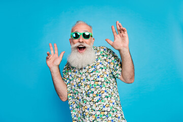 Photo of old senior aged gray bearded hairstyle macho man wear tropical shirt green sunglass shocked unexpected dance isolated on blue color background