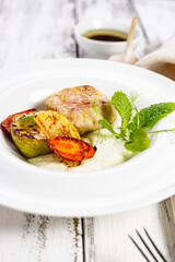 Delicious and healthy food. Close-up homemade turkey cutlets and grilled vegetables. Cheese sauce with garlic and olive oil. Food composition on white wooden background. Vertical shot. Copy space
