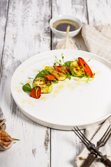 Appetizing grilled vegetables on a white plate. Vegan food. Grilled zucchini and carrots with herbs and spicy sauce. Delicious and healthy food.