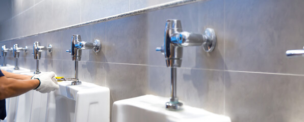 A handyman or plumber is using a wrench to fix or repair leaking water pipes, faucets or valves in...