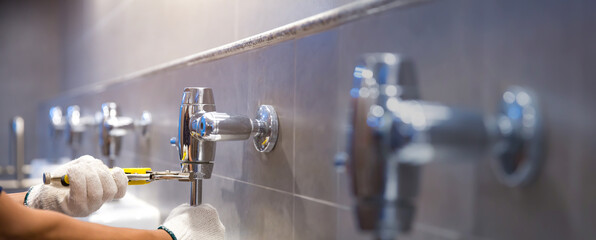 A handyman or plumber is using a wrench to fix or repair leaking water pipes, faucets or valves in toilet bowls and sinks