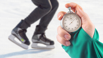 measuring speed on skates with a stopwatch. hand with a stopwatch on the background of the legs of...