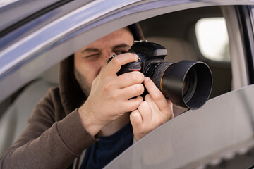 Male driver photographing with slr camera from car, Private detective taking photos - obrazy, fototapety, plakaty