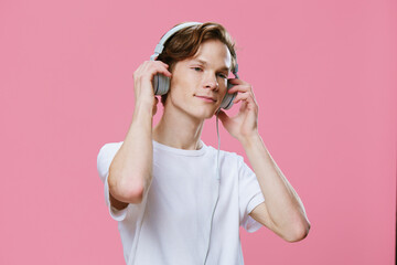 a teenager listens to music on headphones, in pleasure and holding his hands on the headphones