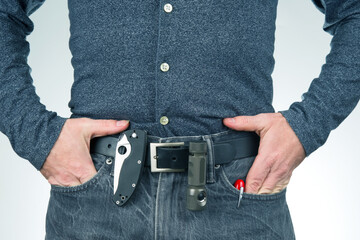 man in jeans on a leather belt with a flashlight and a knife. survival items.