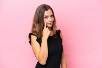 Young caucasian woman isolated on pink background showing something