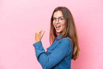 Young caucasian woman isolated on pink background celebrating a victory