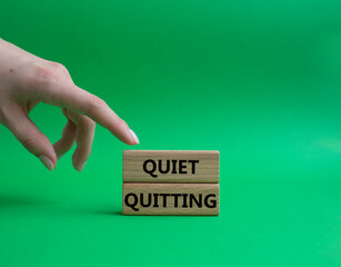 Quiet quitting symbol. Concept word Quiet quitting on wooden blocks. Beautiful green background. Businessman hand. Business and Quiet quitting concept. Copy space.