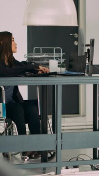 Vertical video: Database programer with physical disability writing code on computer screen, coding artificial intelligence algorithm. Engineer with impairment programming database on terminal window.