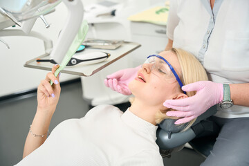 Woman patient examining her teeth in the mirror