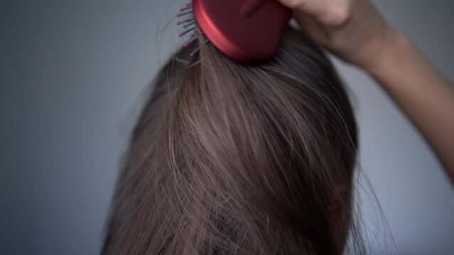 A woman combs her hair. Gray hairs on the head of a young girl. Long gray hair. The initial stage of gray hair. The problem of gray hair in women.