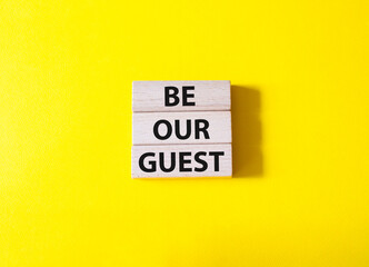 Be our guest symbol. Concept word Be our guest on wooden blocks. Beautiful yellow background. Business and Be our guest concept. Copy space