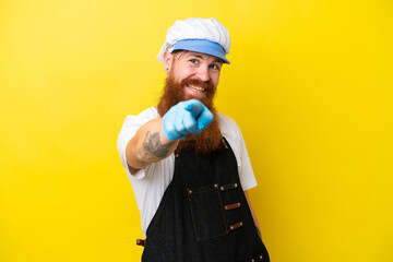 Fishmonger wearing an apron isolated on yellow background points finger at you with a confident expression