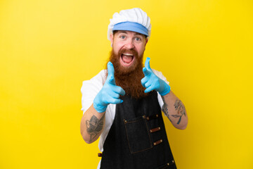 Fishmonger wearing an apron isolated on yellow background pointing to the front and smiling