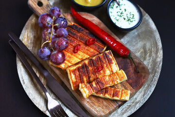 Grilled cheese with chili pepper on a wooden board.
