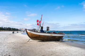 Ostseebad Binz an einem sonnigen Winternachmittag ein Fischerboot liegt am Strand - obrazy, fototapety, plakaty