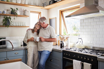 Love, kitchen and senior couple relax with cup of coffee, tea or hot drink while bonding and...