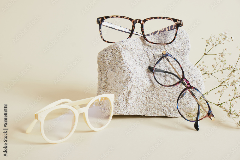 Wall mural several different trebdy eye glasses with fashion frames and concrete podium on beige background