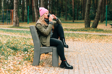 Woman sitting on outdoor in the forest drinking a cup of hot coffee . Beautiful female relax and enjoy outdoor activity lifestyle in nature on autumn travel vacation