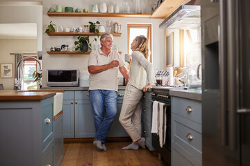 Relax, coffee and elderly couple in a kitchen, bonding and talking in their home together. Love,...