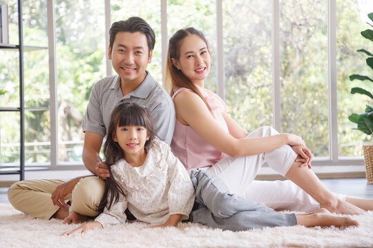 Real estate and mortgage concept : Family with child having fun in new home. Joyful first-time buyers in living room. Real estate, residential mortgage, moving into dream house.