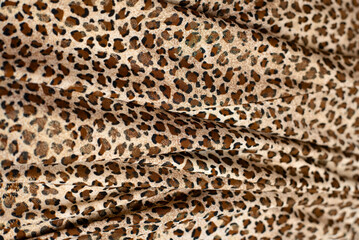 Wavy beautiful fabric with wild animal leopard or cheetah print on it, popular fabric among women with spots, leopard skin, copy space