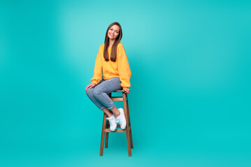 Full length photo of young attractive pretty nice woman sitting chair wear yellow sweater denim...