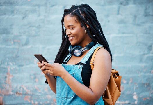 Black woman, smile and phone of a student from Jamaica with technology and headphones. Happy, urban and gen z person using 5g internet, web and social media app scroll while texting with happiness - Powered by Adobe