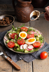 Female hand pouring with sause  delicious vegetable salad with chicken eggs and croutons on a wooden table. Close up