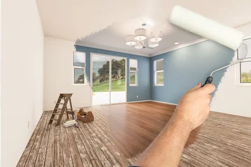 Fotobehang Before and After of Man Painting Roller to Reveal Newly Remodeled Room with Fresh Blue Paint and New Floors. © Andy Dean