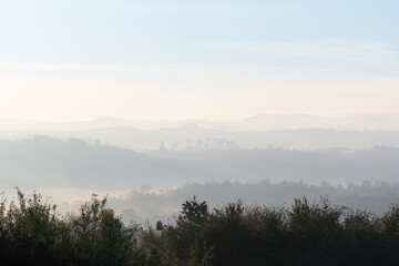 Fototapeta premium Hills with forest in fog at autumn morning, misty forest layers in autumn