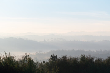 Hills with forest in fog at autumn morning, misty forest layers in autumn