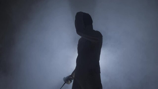 wearing a protective mask and holding a fencing foil in his hand