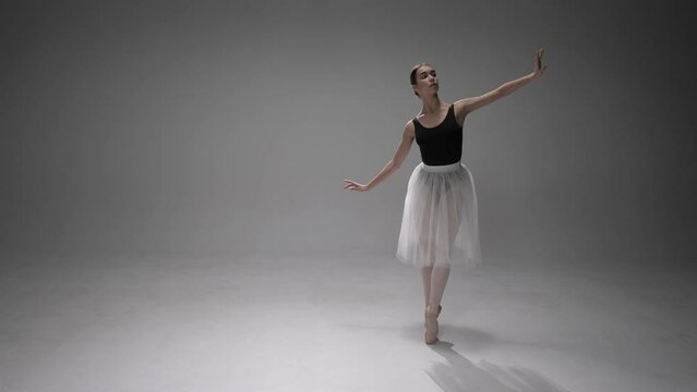 Ballerina. White background. Girl does dance steps in the stage costume.