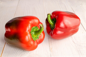 Two red organic, bell peppers, close-up, on a wooden table.