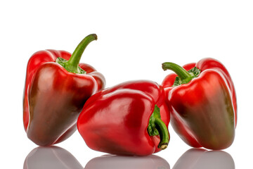 Three red organic, bell peppers, close-up, on a wooden table.