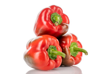 Three red organic, bell peppers, close-up, on a wooden table.
