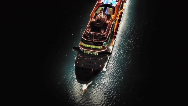 Aerial view of illuminated large cruise ship in the sea at night