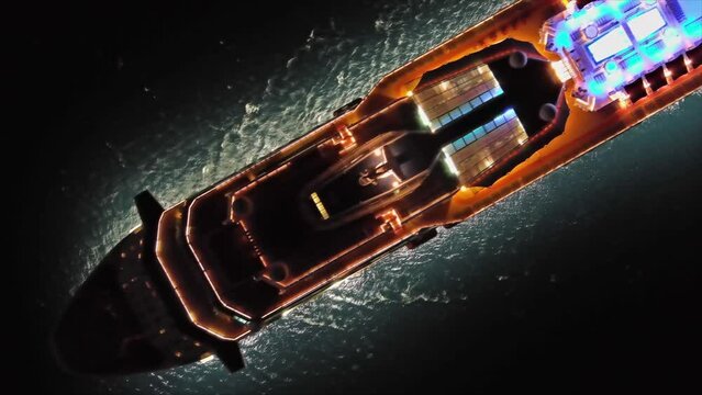 Aerial top view of illuminated large cruise ship in the sea at night