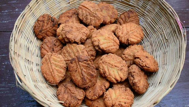 Thekua , an Indian sweet dish or a snacks in bamboo or wooden basket or tokri in wooden table. popular in bihar jharkhand. Prashad in chhath maha parv or puja or festival. selective focus.