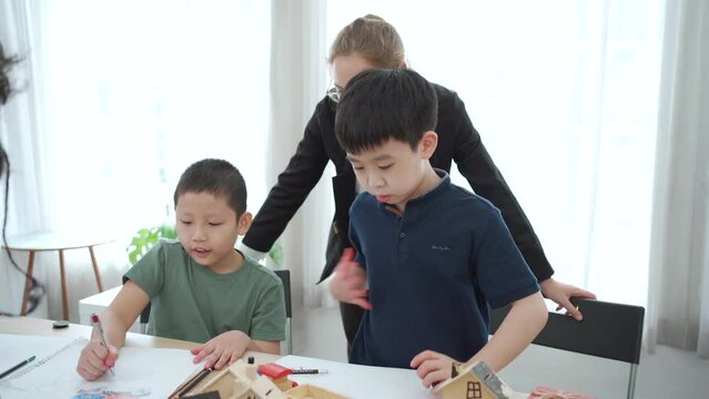 Group of little boys and girls enjoy drawing and painting together in classroom.