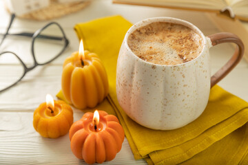 Autumn composition, hot cup of coffee, candles, candlesticks miniature house on a wooden table. Seasonal, morning hot coffee. Relaxing and still life concept. Cozy interior decor.