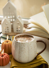 Autumn composition, hot cup of coffee, candles, candlesticks miniature house on a wooden table. Seasonal, morning hot coffee. Relaxing and still life concept. Cozy interior decor.