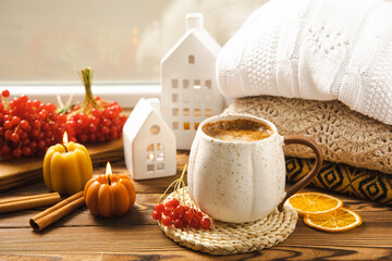 Autumn composition, a hot cup of coffee, candles, candlesticks, a miniature house and a warm sweater on a wooden table.Seasonal, morning hot coffee. Relaxing and still life concept.Cozy interior decor