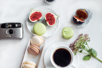 aesthetic film camera flatlay, cups of coffee, figs and macarons on a white background, top view