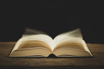 open bible on the antique wooden table in a dark room with light abstract style