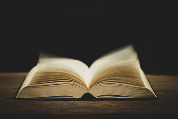open bible on the antique wooden table in a dark room with light abstract style