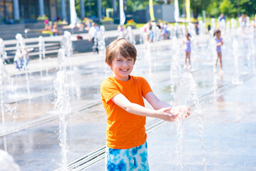 happy child plays in a dry fountain. joyful smiling wet boy in the fountain